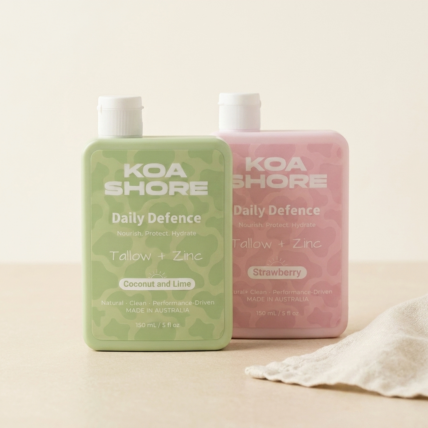 Koa Shore Daily Defence 2-pack bundle - Coconut and Lime and Strawberry bottles on warm sand with linen