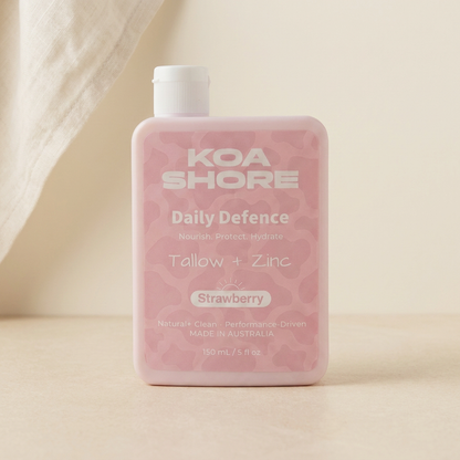 Koa Shore Daily Defence Strawberry bottle on warm sand with linen