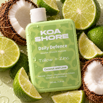 KOA SHORE Daily Defence Coconut and Lime bottle nestled among fresh limes and coconut.